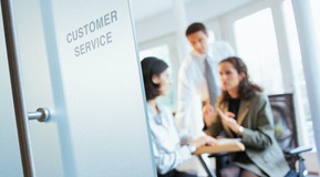 Businessman and two businesswomen discussing in customer service office